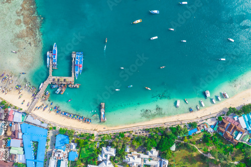 Flying above busy tropical island port filled with boats and fer