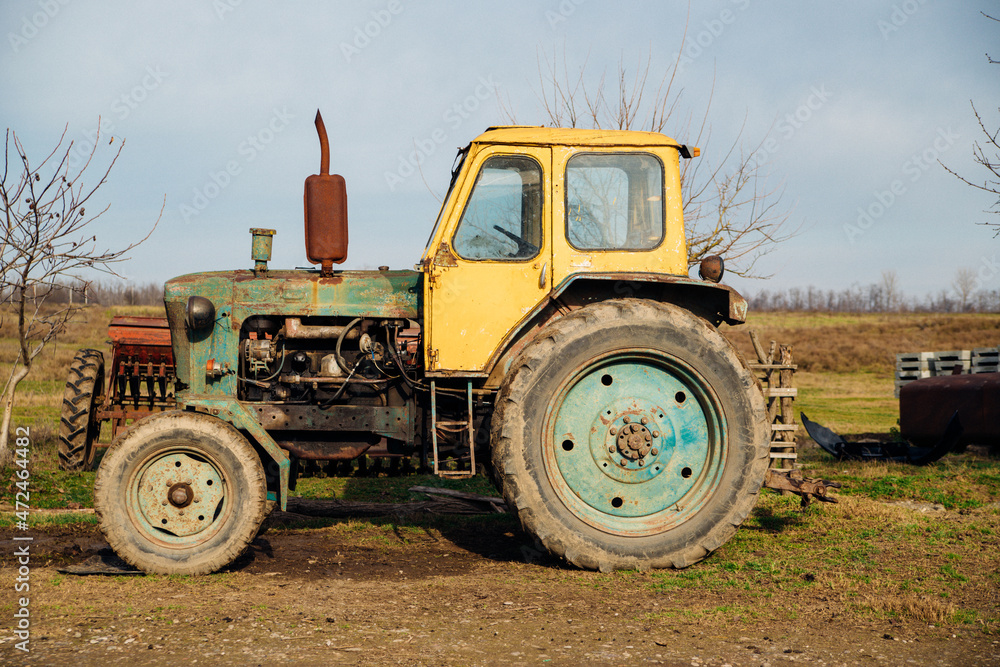 A yellow tractor stands in the countryside. Agriculture and farming.An old tractor. A yellow tractor stands in the countryside. Agriculture and farming.An old tractor.
