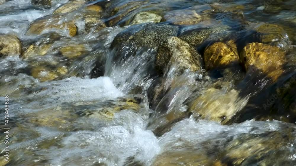 A stream of water with foam and a rocky bottom of a mountain river. A stream of water with foam and a rocky bottom of a mountain river.