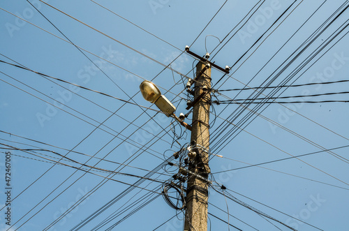 Many wires attached to the electric pole, the chaos of cables and wires on an electric pole, blue sky background, technological combination concept 