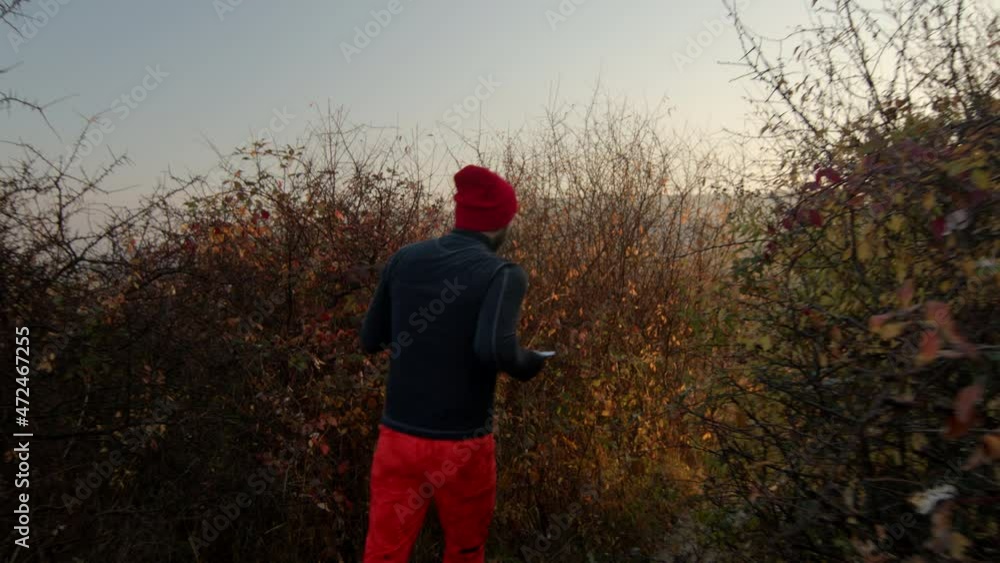 Rear view of mid adult man running through the bushes down hill in sunny autumn morning. Sunset clear blue sky on the background. Rear view of mid adult man running through the bushes down hill in sunny autumn morning. Sunset clear blue sky on the background.