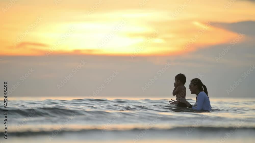 Happy family resting at beach in summer, Mother and baby boy feet at the sea foam at the sunlight water is moving Happy family resting at beach in summer, Mother and baby boy feet at the sea foam at the sunlight water is moving