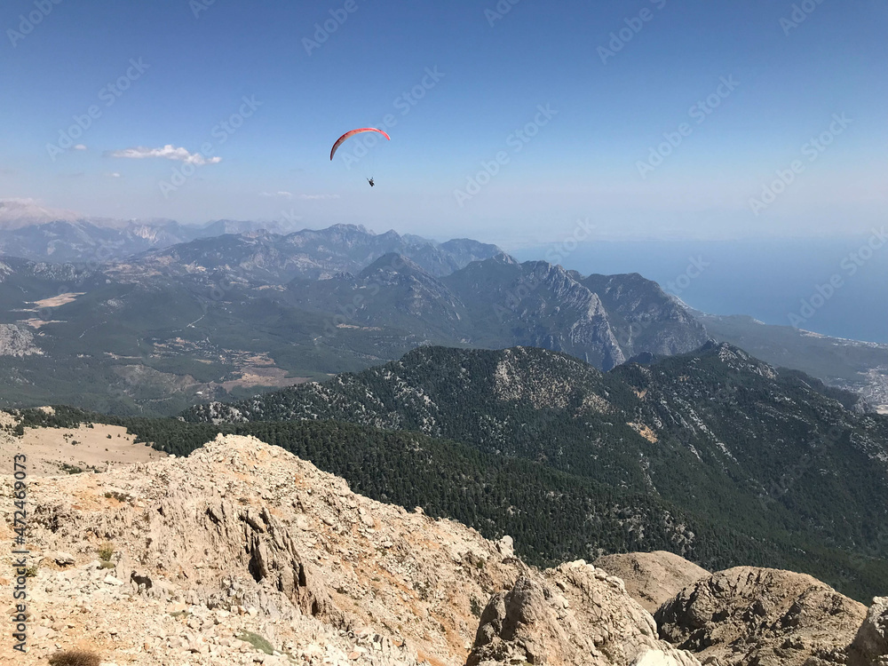 Paragliding in mountains. Freedom to fly in air over mountains with parachute. Paragliding behind blue sky Carpathian Mountains hills range landscape. Active tourist sport People fly using Parachute Paragliding in mountains. Freedom to fly in air over mountains with parachute. Paragliding behind blue sky Carpathian Mountains hills range landscape. Active tourist sport People fly using Parachute