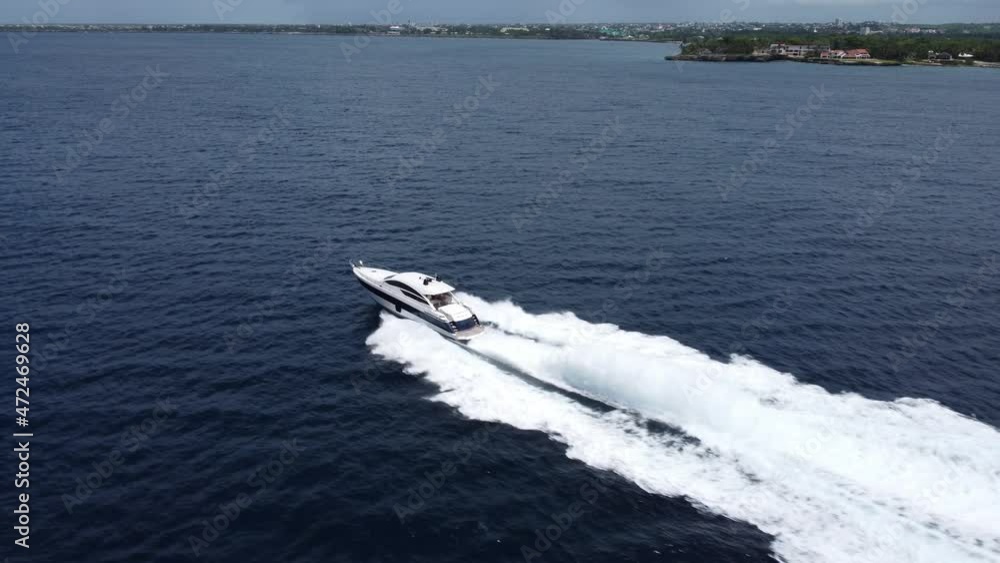 Aerial tracking of speedboat sailing while leavinge white wake on blue sea of La Romana in Dominican Republic Aerial tracking of speedboat sailing while leavinge white wake on blue sea of La Romana in Dominican Republic