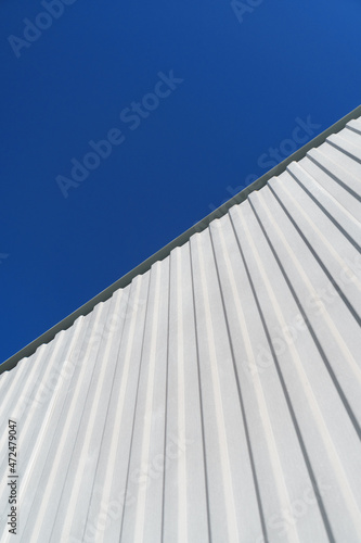 Textured white metal structures diagonally against a blue sky.