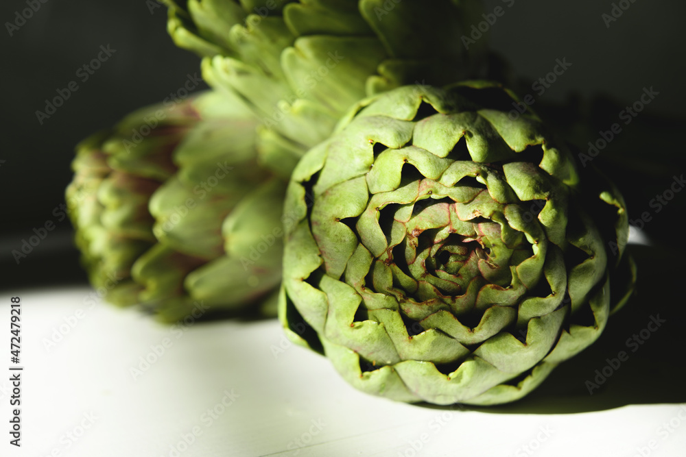 Fototapeta premium Fresh artichoke on a white wooden background with beautiful daylight shadow