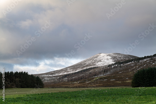 DUFFTOWN, MORAY, SCOTLAND - 1 DECEMBER 2021: This is the peak of Moray, Ben Rinnes with some snow coverage and the sun peeking at times in Dufftown, Moray, Scotland on 1 December 2021. photo