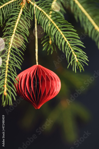 Red Christmas honeycomb paper decoration on fir branch. photo