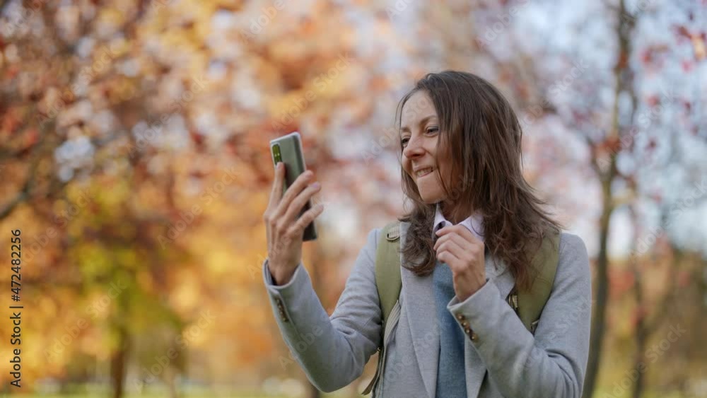 a middle-aged woman smiles confidently while making a video call on the street a middle-aged woman smiles confidently while making a video call on the street