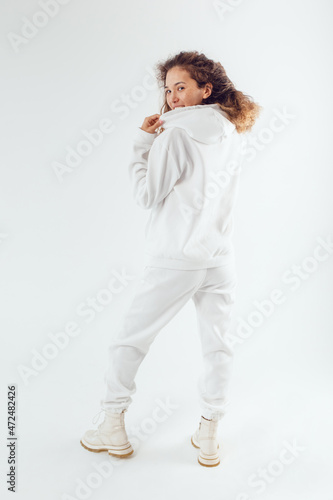 Woman with thick curly hair in a white suit from a hoodie and sweatpants back view.
