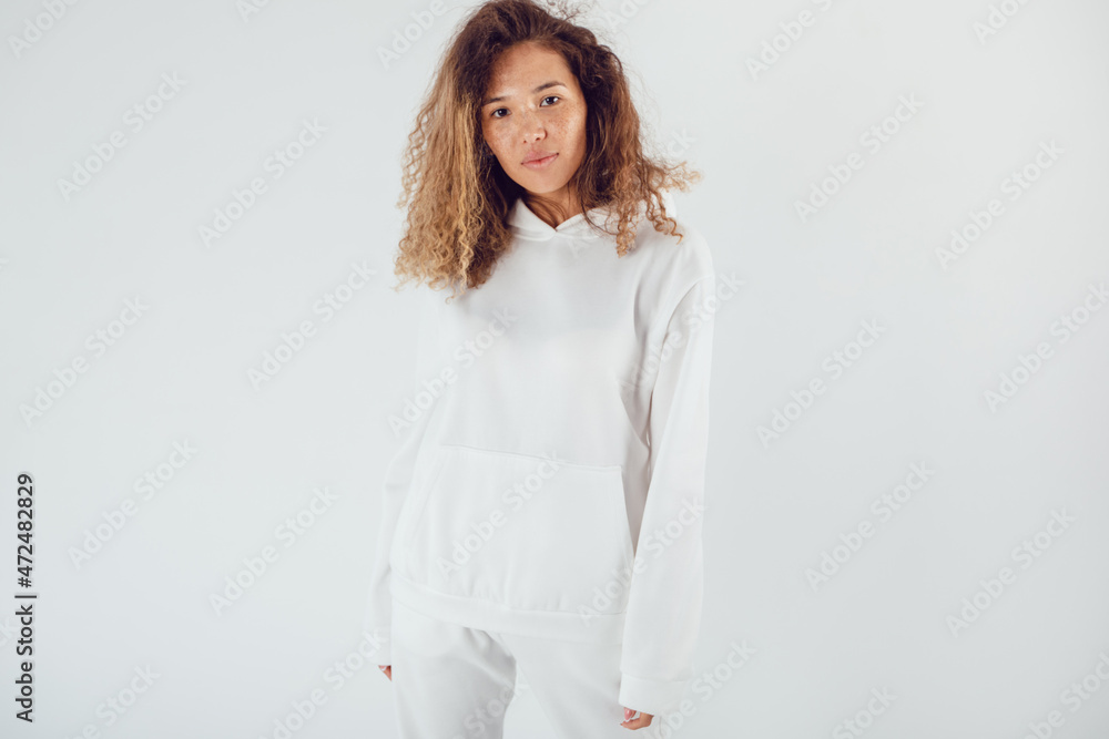 Attractive woman with thick curly hair in a white suit of hoodies and sweatpants. Mock-up. Attractive woman with thick curly hair in a white suit of hoodies and sweatpants. Mock-up.