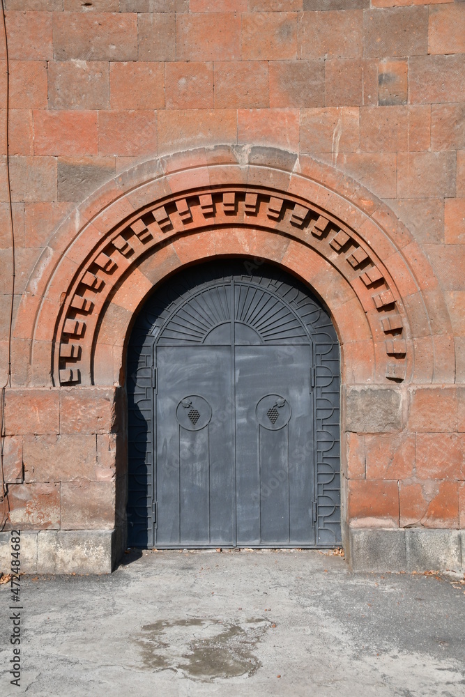 Beautiful metal gate in a stone wall. The arch of the gate is stone.