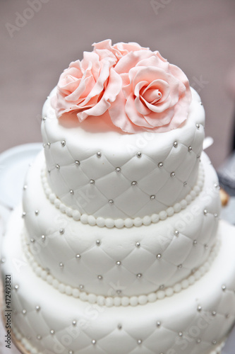 a multi level white wedding cake and pink flowers on top. Big cake.