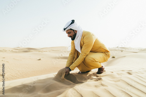 Man wearing traditional uae clothes spending time in the desert