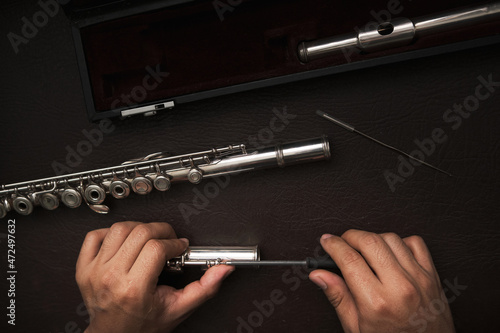 top view of a man's hands disassembling the keys of a flute to repair it.
