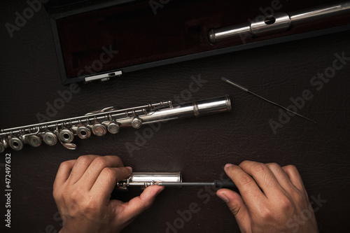 top view of a man's hands disassembling the keys of a flute to repair it. photo