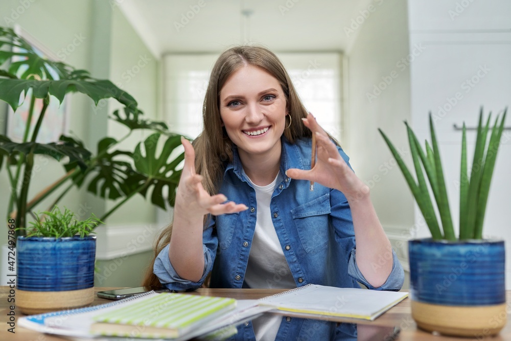 Positive smiling female university student talking looking at webcam, at home. Positive smiling female university student talking looking at webcam, at home.