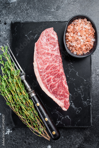 Wagyu raw sirloin steak, kobe beef meat on marble board. Black background. Top view