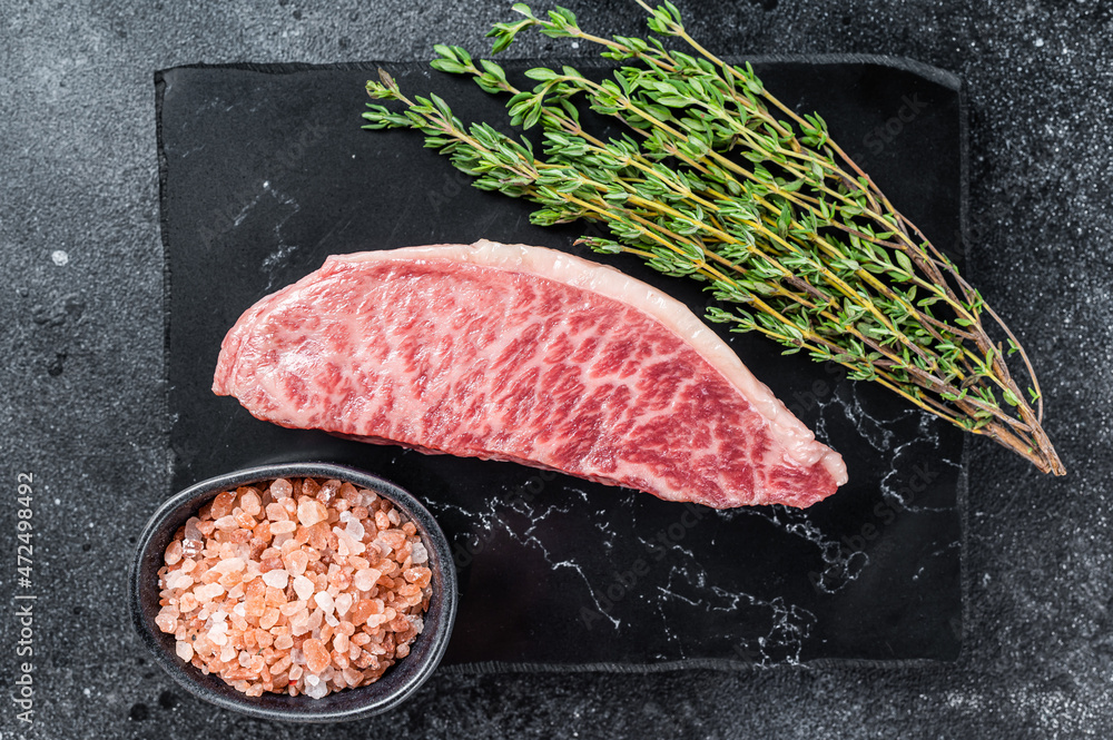 Wagyu raw sirloin steak, kobe beef meat on marble board. Black background. Top view - obrazy, fototapety, plakaty 