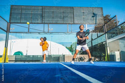 Mixed padel match in a blue grass padel court - .Beautiful girl and handsome man playing padel outdoor