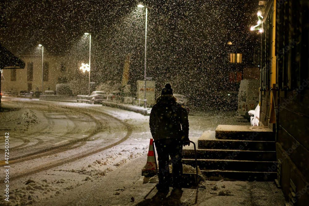 Personne nettoyant la route pendant une forte tomber de neige la nuit