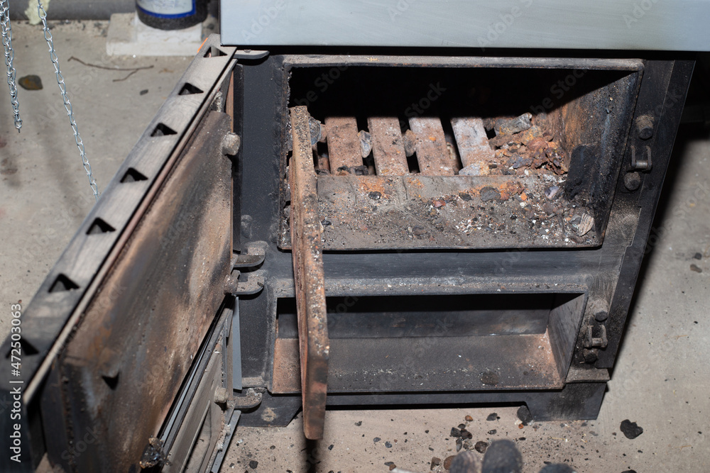 Cleaning the solid fuel boiler from the remains of firewood and coal. Boiler with an open damper. Heating efficiency in the house Cleaning the solid fuel boiler from the remains of firewood and coal. Boiler with an open damper. Heating efficiency in the house