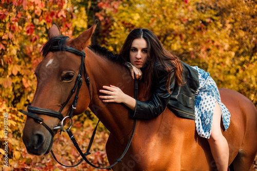 Young beautiful girl in dress riding a horse in the autumn forest