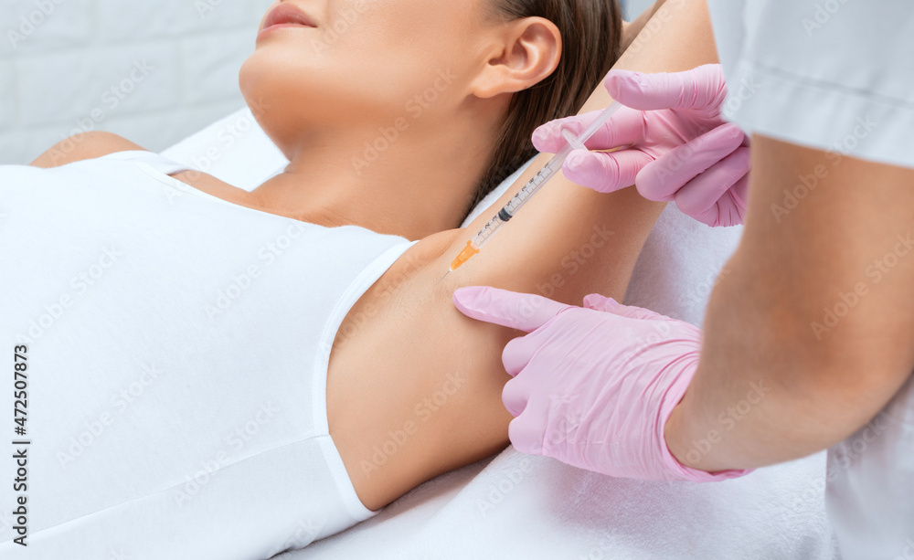 The doctor makes injections of botulinum toxin in the underarm area against hyperhidrosis. Women's cosmetology concept. The doctor makes injections of botulinum toxin in the underarm area against hyperhidrosis. Women's cosmetology concept.