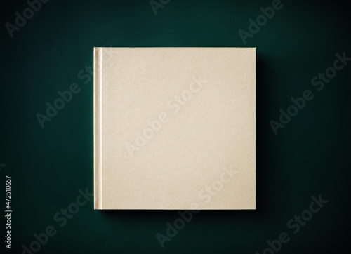 Blank closed hardcover book on green background. Flat lay.