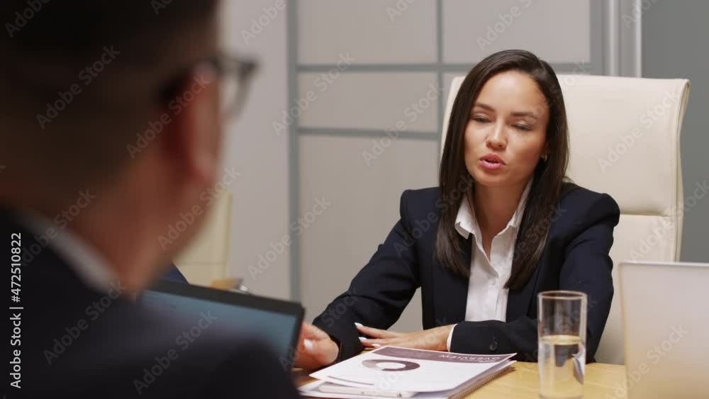 Over shoulder shot of businessman discussing finances with female executive in suit during meeting Over shoulder shot of businessman discussing finances with female executive in suit during meeting