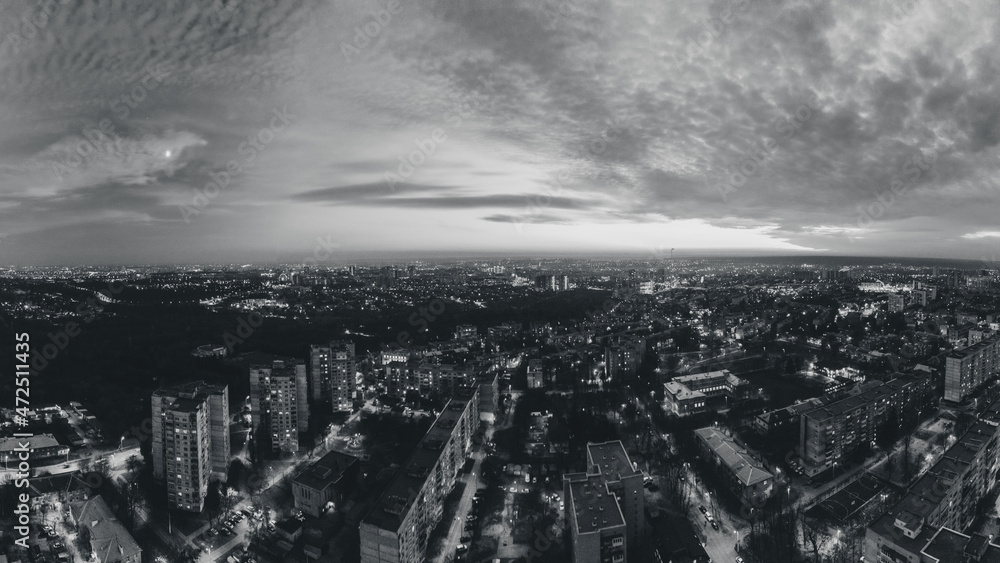 Night lights on streets of residential district and moody cloudy sky. Aerial grayscale sunset scenic panorama on Kharkiv city, Pavlove pole
