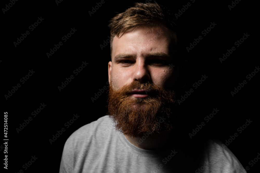 Close-up portrait of a handsome a brunette brutal bearded man in a grey t-shirt. Stylish and handsome man with a beard.