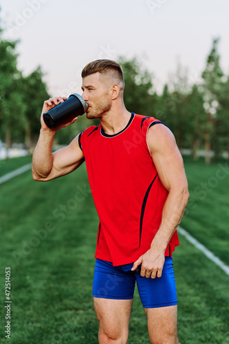 Cheerful sporty man in the park on green grass doing exercises