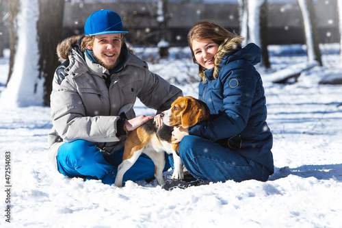 Young family, couple in love on a winter walk with a beagle puppy.