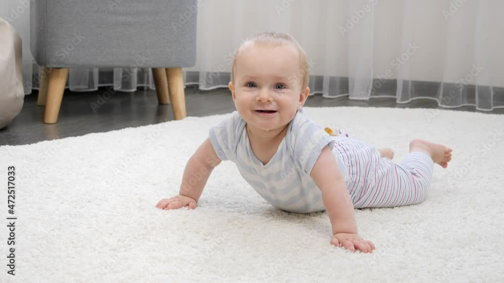 Happy smiling baby boy lying on soft carpet in living room. Concept of child development, happy childhood and fun at home. Happy smiling baby boy lying on soft carpet in living room. Concept of child development, happy childhood and fun at home.