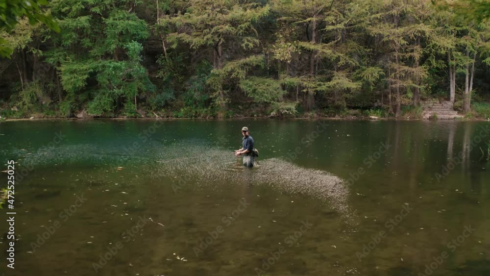 Texas flyfisherman stripping fly rod while wading in a beautiful river with lush tree scenery near shore rippling the water, drone aerial drone shot flying past stand up paddle board in 4k Texas flyfisherman stripping fly rod while wading in a beautiful river with lush tree scenery near shore rippling the water, drone aerial drone shot flying past stand up paddle board in 4k