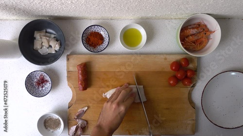 Male hands preparing squid seafood for Spanish Paella on wooden cutitng board photo