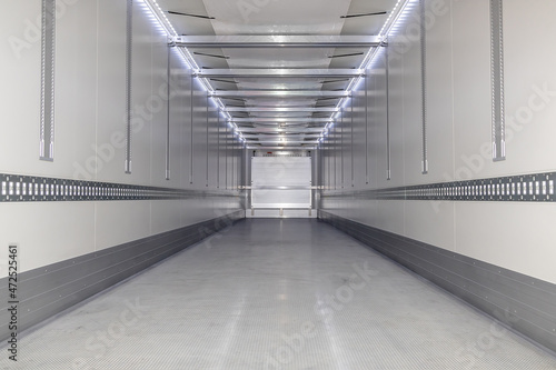 A big new empty refrigerated trailer inside. Inner space of the semi-trailer for transporting frozen food. Lighted cargo area for cargo placement. Lower angle shot