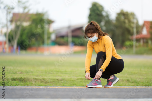 woman tying her running shoes and wearing medical mask to protect Coronavirus(Covid-19) pandemic.