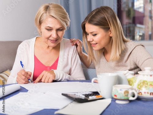 Daughter helps mother to lead home accounting. High quality photo