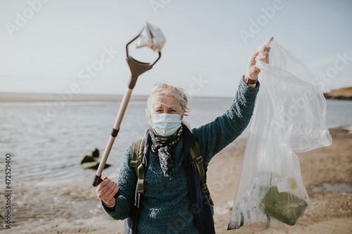 фотографія Beach cleanup volunteer carrying garbage bag for environment campaign