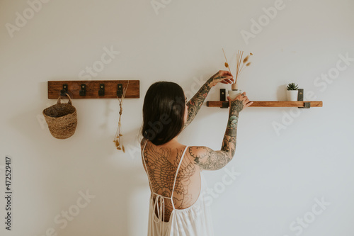 Obraz na plátně Woman placing aroma diffuser on wall shelf