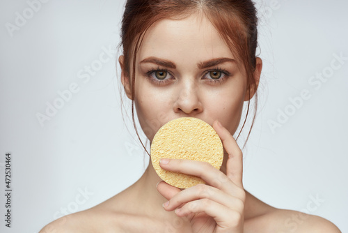 woman with a sponge in her hands bare shoulders skin care closeup