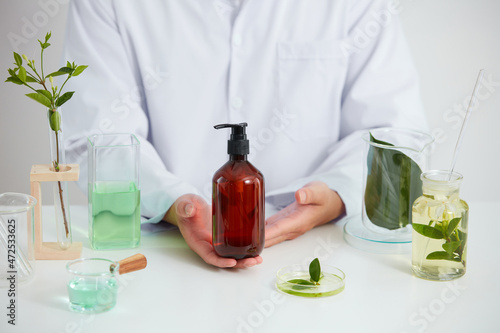 Plants extract in laboratory , petri dish in a white background , green leaf in a test tube and scientist for cosmetic jar advertising , photography science concept , front view