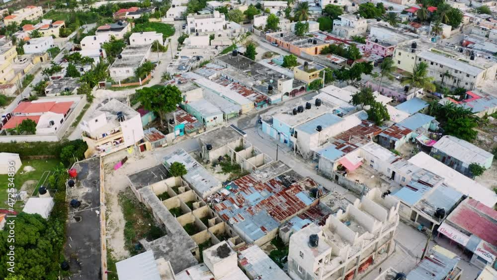 People are deprived of social services and have no rights. Flimsy buildings with gray rusty roofs sit tightly together. A workers' quarter on the outskirts of a city with poor streets. People are deprived of social services and have no rights. Flimsy buildings with gray rusty roofs sit tightly together. A workers' quarter on the outskirts of a city with poor streets.