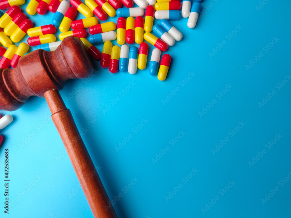 Pill capsules and gavel on a blue background with copy space. Pill capsules and gavel on a blue background with copy space.