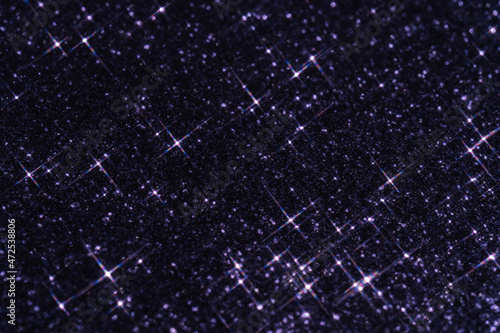Abstract violet background with sparkles in the shape of stars.