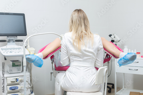 Back view of a gynecologist conducting a routine examination of a girl on a gynecological chair using modern medical technologies photo