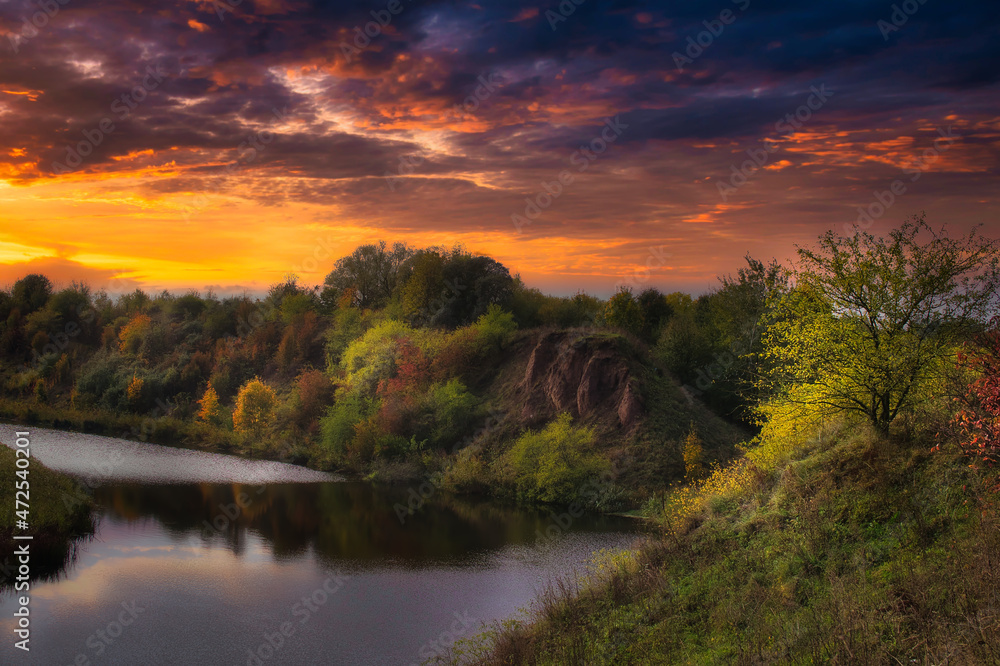 Vivid orange sunset over a tranquil river or creek in autumn