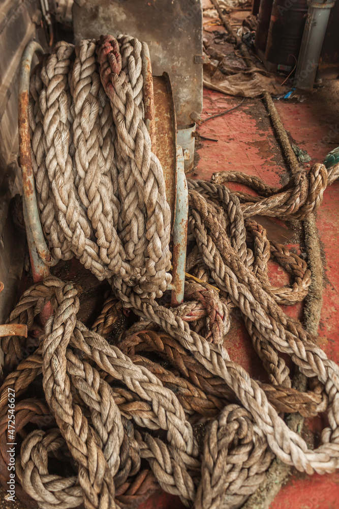 Dirty ship's rope uncoiled lying among the debris on board the shipwrecked ship. View from the ship.